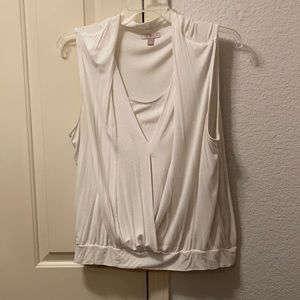 Sleeveless white shirt with inset and overlap.